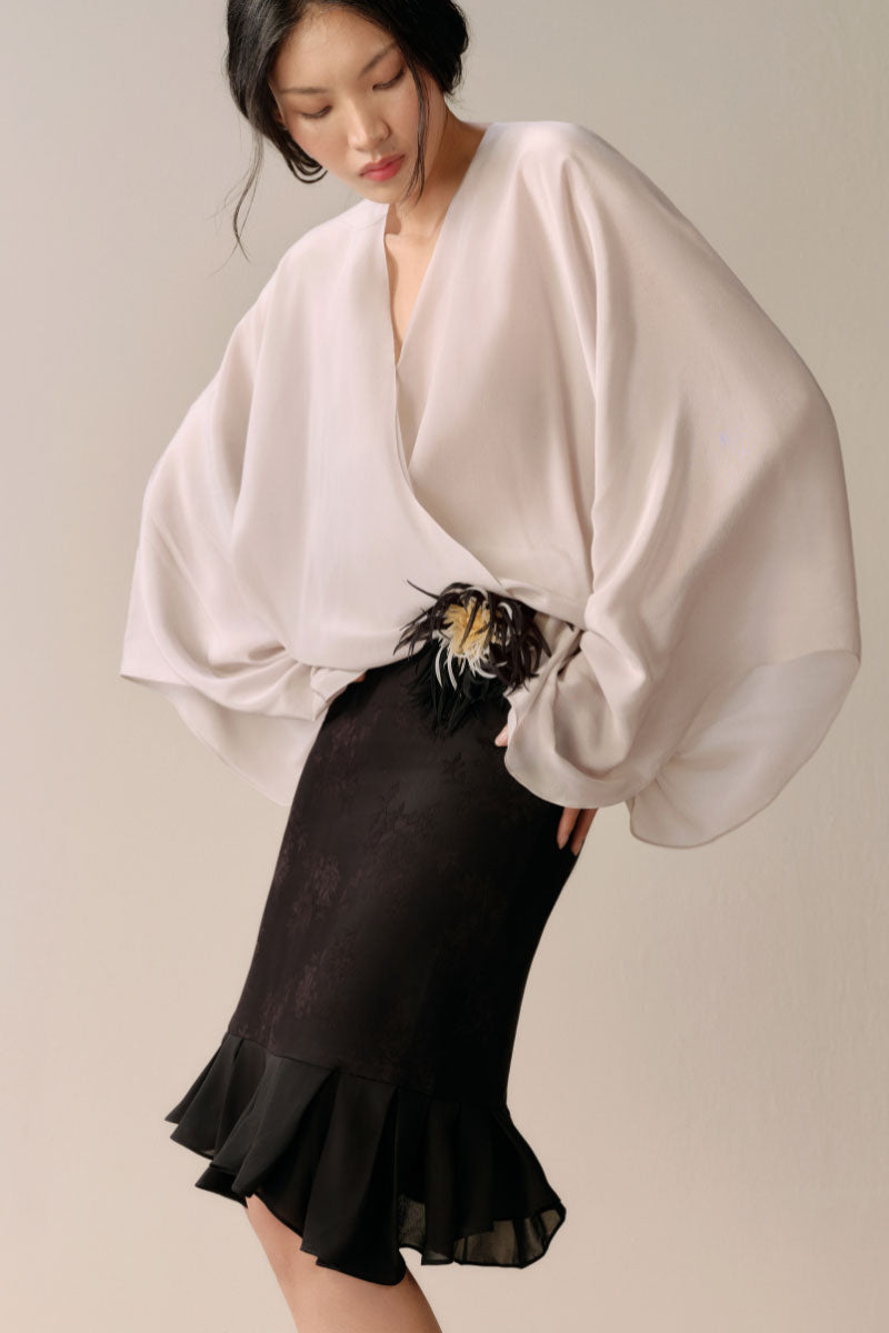 Black Levia trumpet midi skirt displayed on a model, showcasing its fitted waist and flared hem in a stylish silhouette.