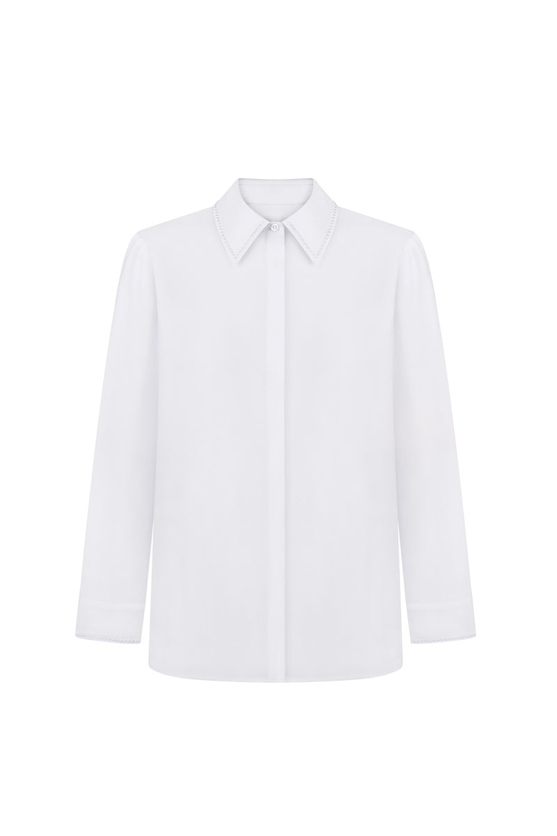 White embroidered shirt by Delegan, featuring detailed embroidery on the front and classic collar, displayed on a hanger.