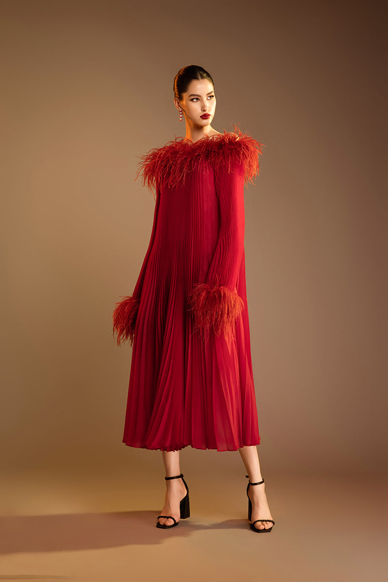 Red Valenciani midi dress with ostrich feather trim and pleated design, showcasing elegant fabric and detailed craftsmanship.