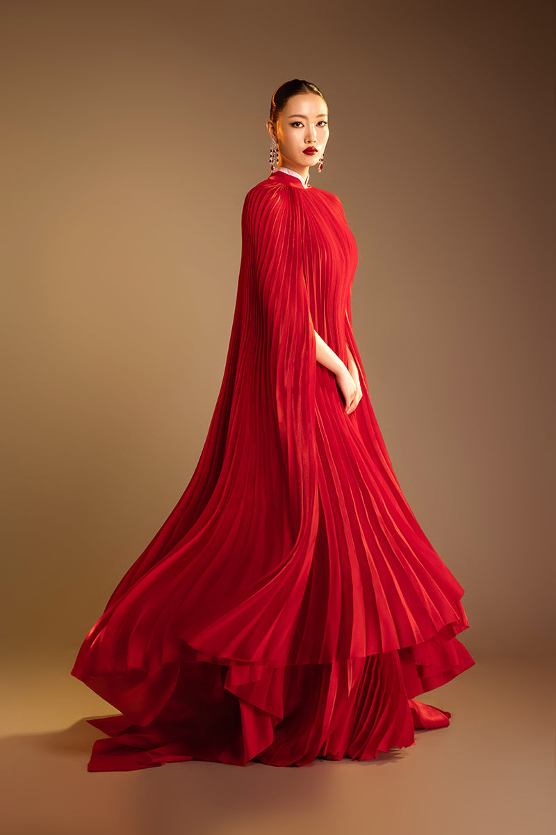 Red Valenciani Sunray pleated high-neck cape gown with flowing fabric and elegant design, perfect for formal occasions.