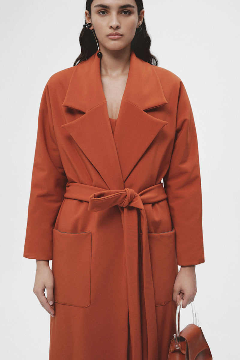 JC Pajares long coat with side pockets, stylish and warm, shown hanging on a wooden hanger against a neutral background.