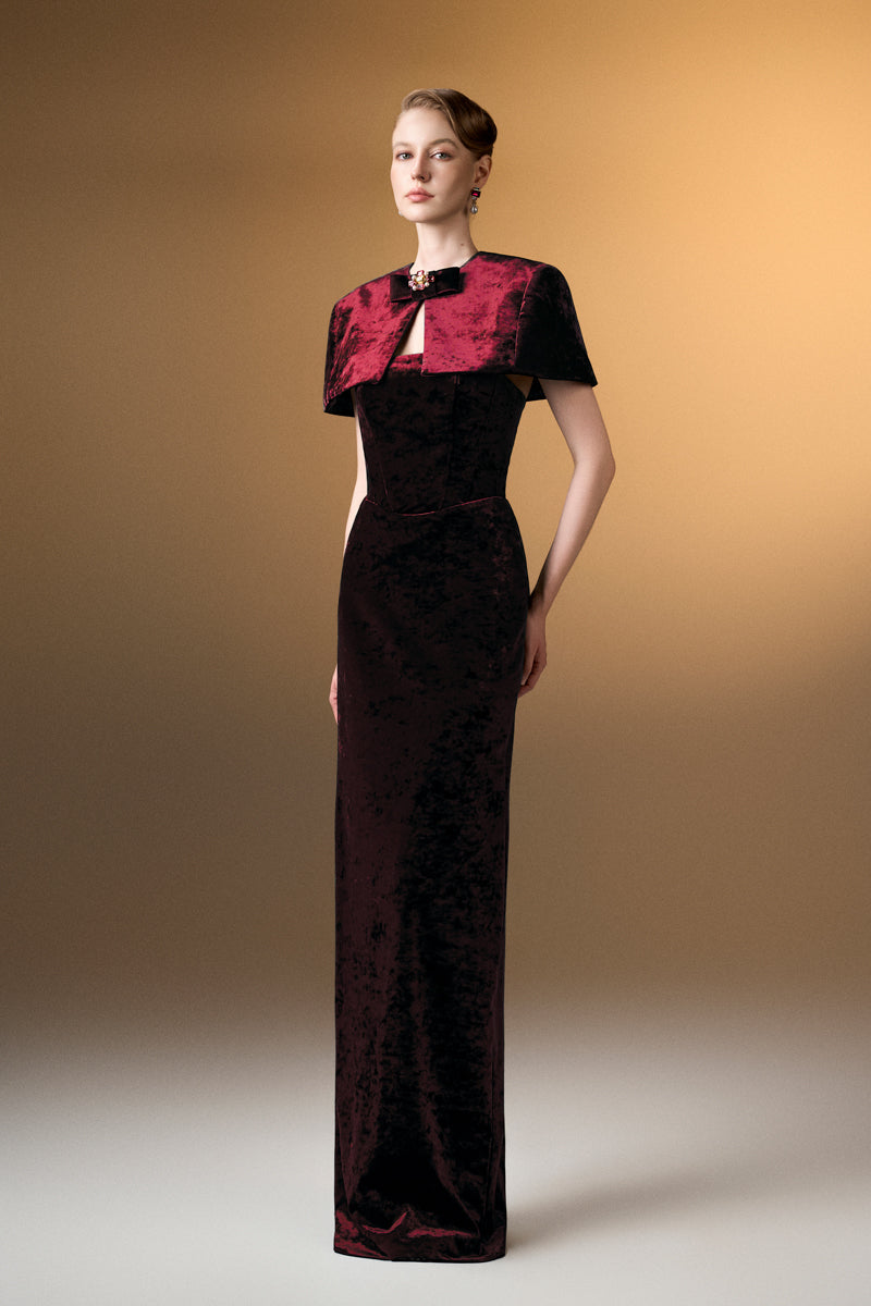 Dark red strapless column gown with mini cape in grain velvet by I.H.F, featuring a sleek silhouette and elegant design.