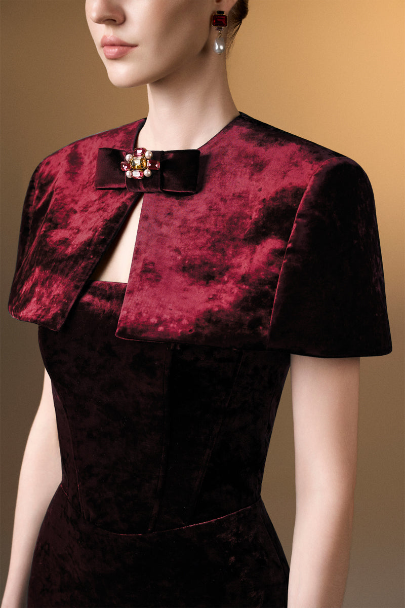 Dark red strapless column gown with a mini cape in grain velvet by I.H.F, featuring a sleek silhouette and elegant design.