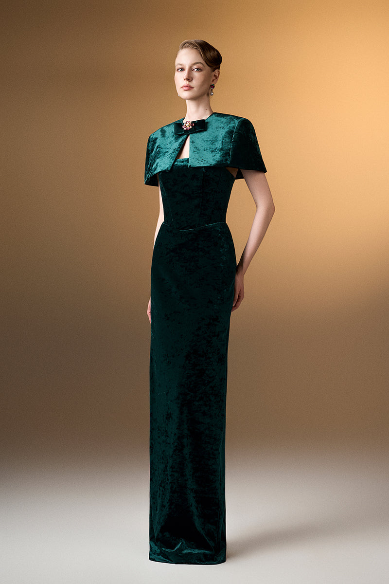 Green strapless column gown with a mini velvet cape from I.H.F, featuring a sleek silhouette and luxurious grain velvet fabric.
