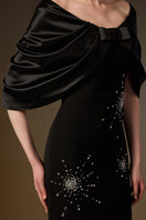 Black ELODIE gown by I.H.F featuring a draped V-neck design and sleek column silhouette in crepe and satin silk fabrics.