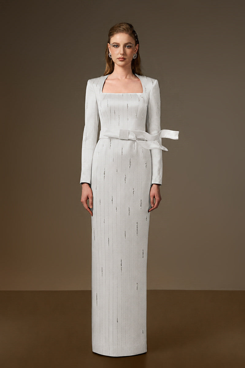 I.H.F white metallic belted train column gown with a trapeze neckline and wind-blown train effect in silky striped fabric.
