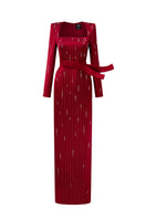 Red metallic belted train column gown by I.H.F featuring a trapeze neck and flowing silk design with a wind-blown train appearance.