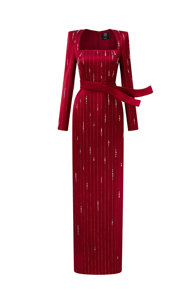 Red metallic belted train column gown by I.H.F featuring a trapeze neck and flowing silk design with a wind-blown train appearance.