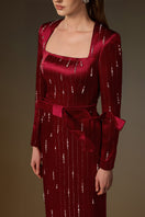 Red metallic belted train column gown by I.H.F with a trapeze neck, flowing silhouette, and wind-blown train effect in silk fabric.