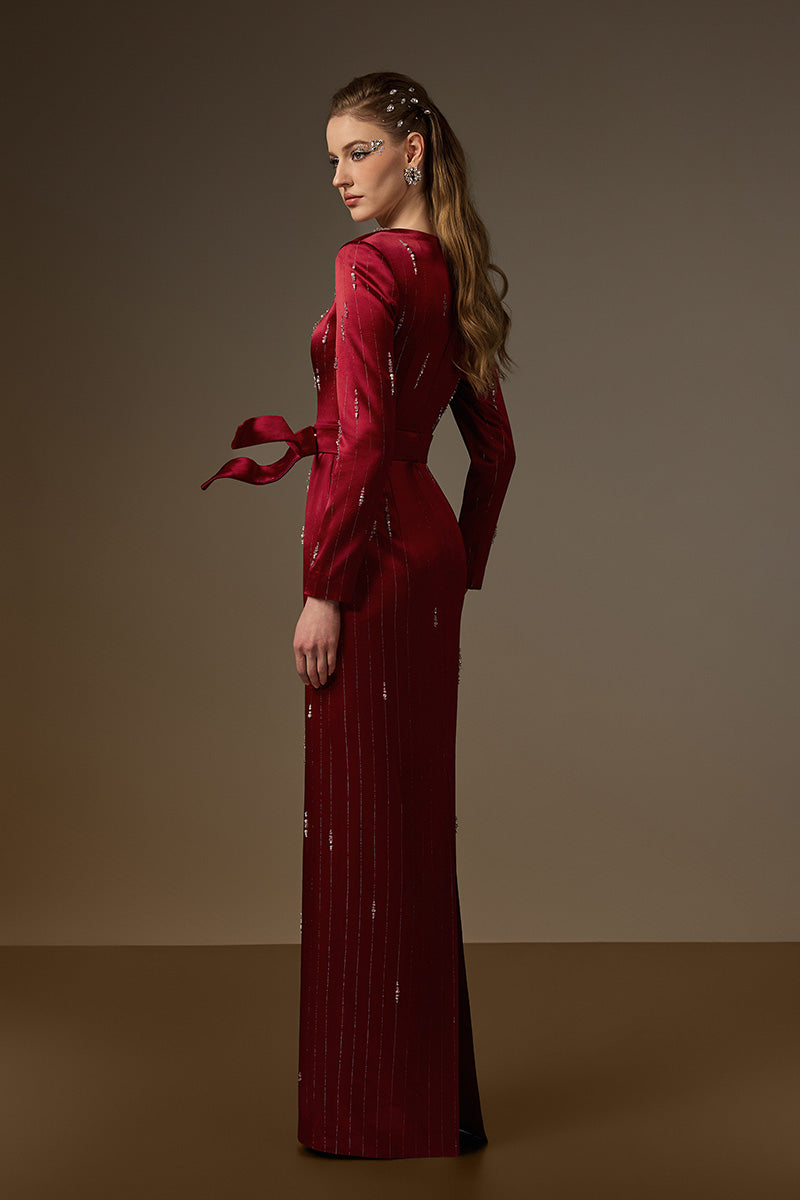 Red metallic belted train column gown by I.H.F featuring a trapeze neckline and flowing silk train, reminiscent of a wind-blown look.