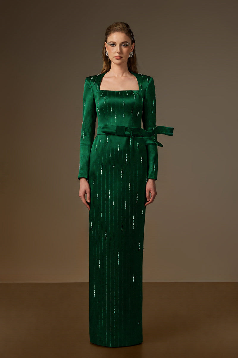 Dark green metallic belted train column gown by I.H.F, with a trapeze neck and flowing wind-blown train silhouette.