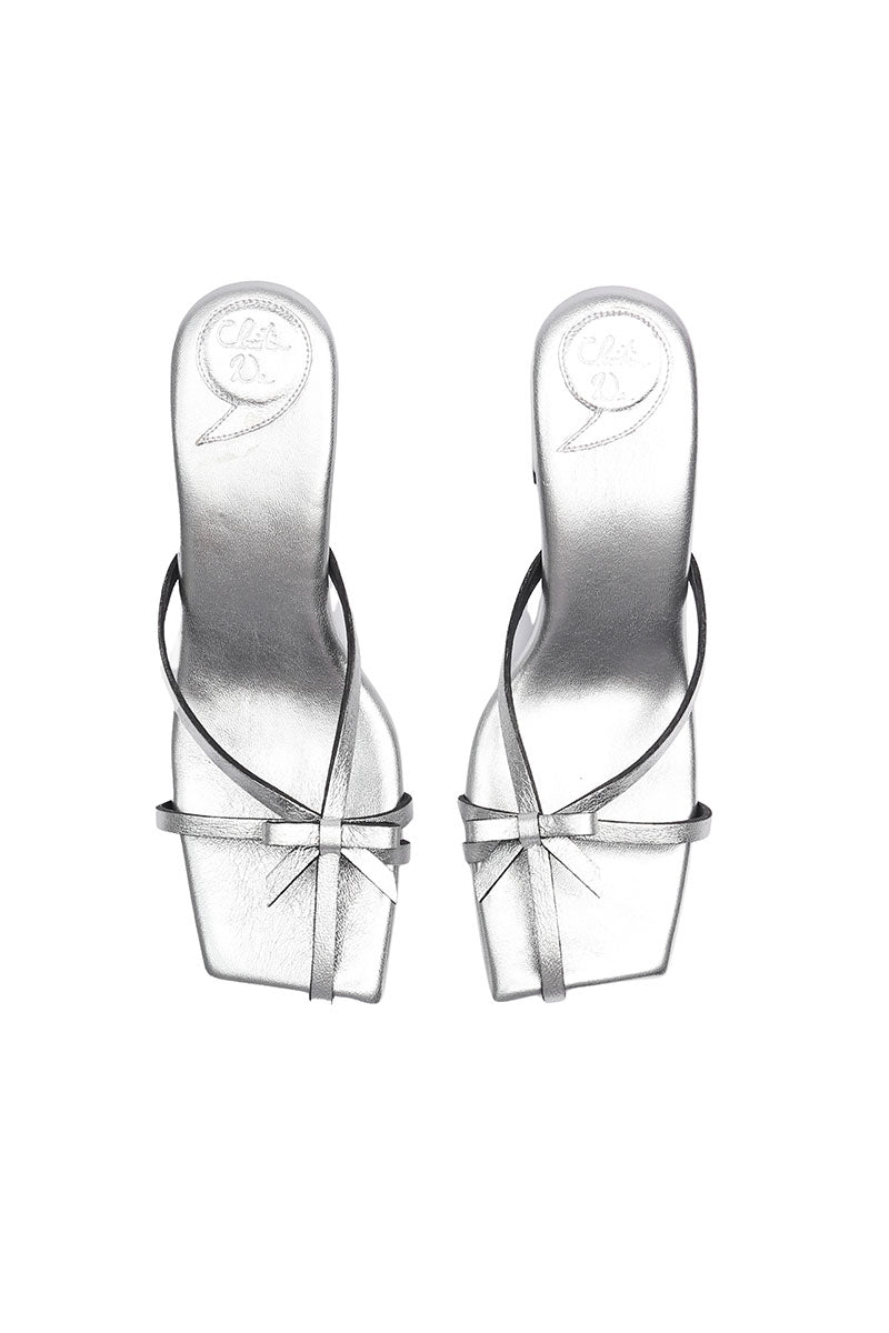 Silver Christin Wu Adrianna sandals with open toes and ankle straps, showcased on a neutral background.