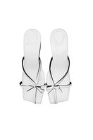 White Adrianna sandals by Christin Wu featuring open toes and ankle straps, shown from a side angle.