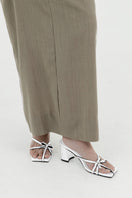 White Christin Wu Adrianna sandals displayed on a model's feet, showcasing stylish open-toe design and ankle straps.