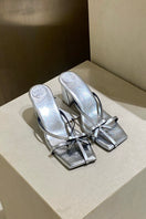 Silver Christin Wu Adrianna sandals styled with casual outfits, featuring open toes and ankle straps.