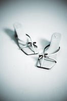White Christin Wu Adrianna sandals displayed on a model, showcasing stylish open-toe design and comfortable flat sole.