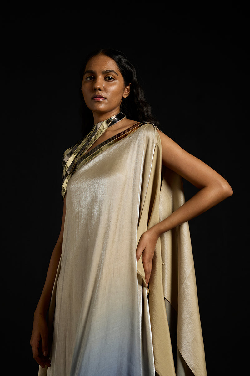Metallic yoke asymmetric kaftan gown by AKHL featuring shiny fabric and elegant drape, displayed on a mannequin.