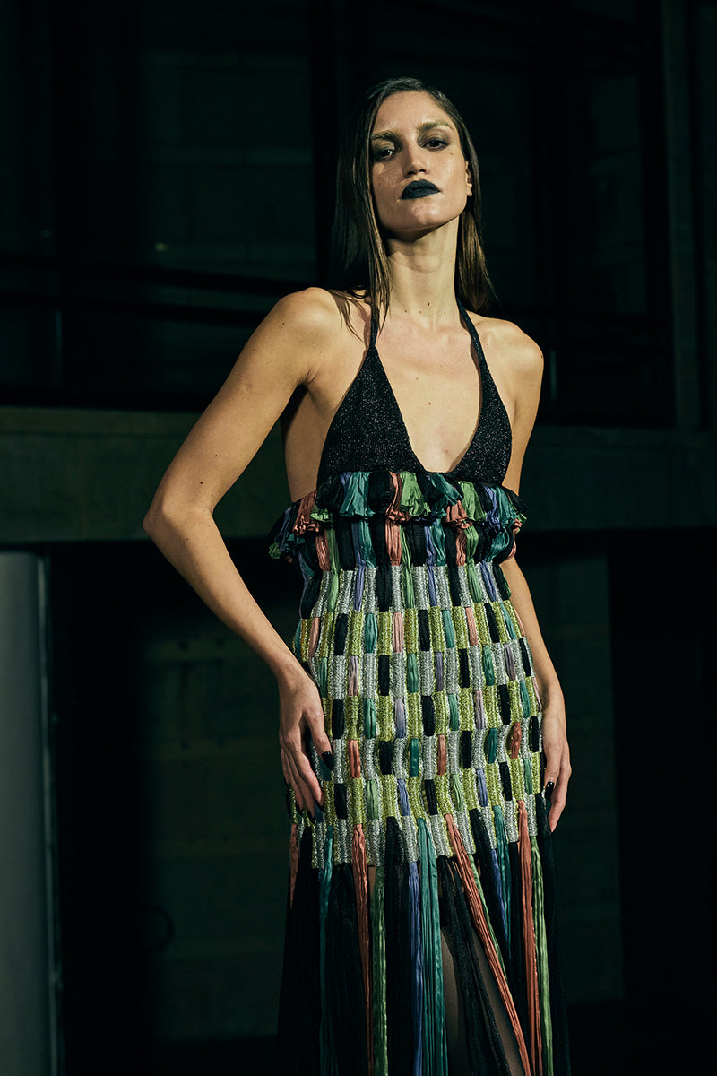 A model wearing a black AKHL dimensional column maxi skirt, showcasing its sleek, flowing design and high-waisted fit.