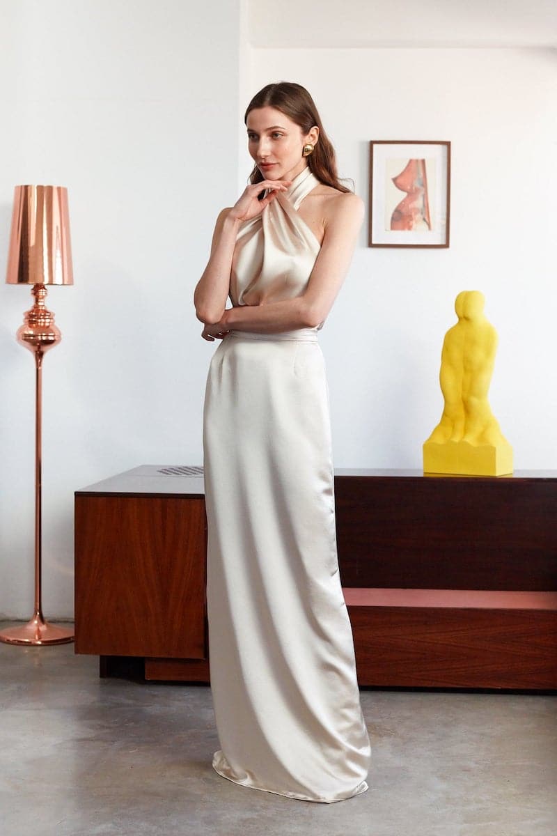Elegant champagne-colored halter neck evening maxi dress by UNDRESS, flowing fabric and sophisticated design perfect for formal occasions.