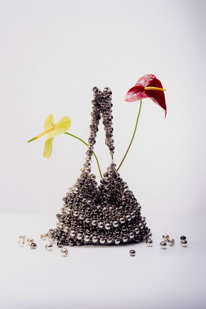 Silver shoulder bag by Millanne Tale with pearl accents, featuring a sleek design and adjustable strap.