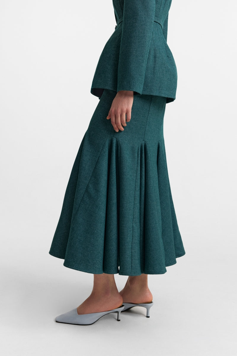 PODYH Secessia teal midi skirt with a fitted waist and flowing fabric, styled for elegant casual wear.