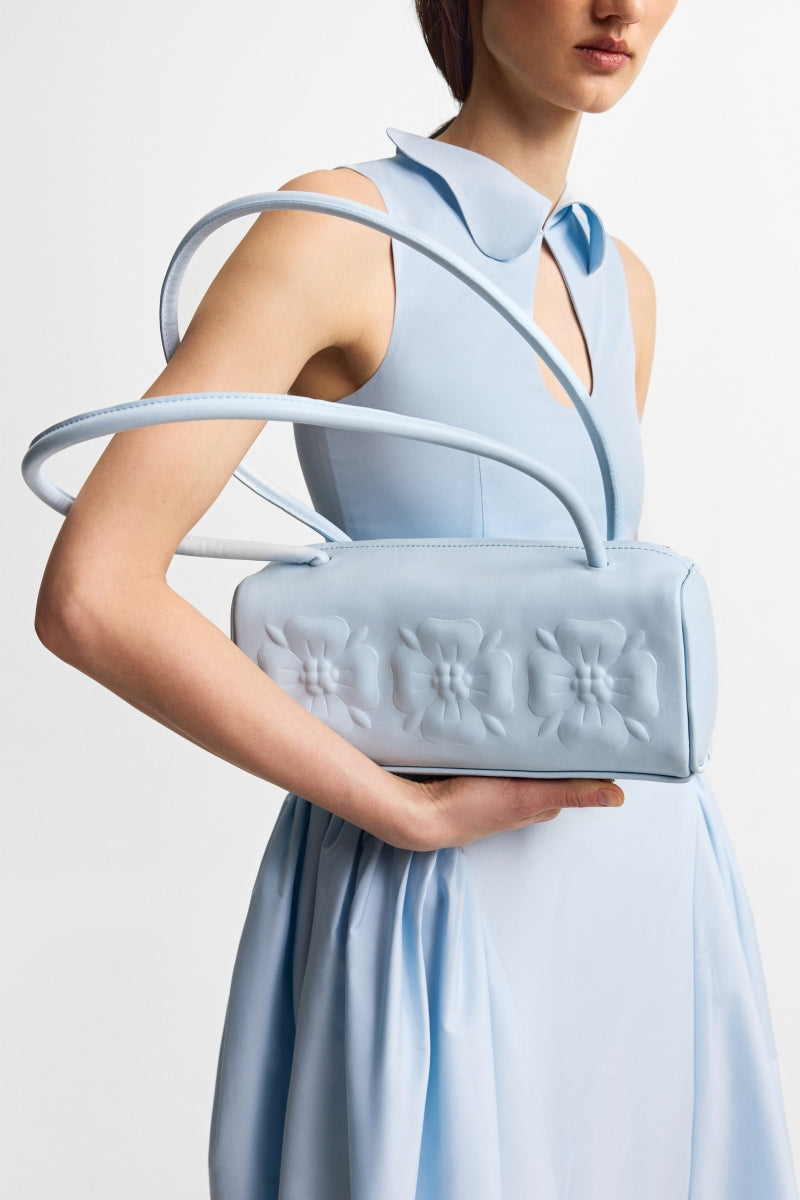 Ice blue PODYH top handle bag with bas relief design, showcasing its elegant shape and textured surface.