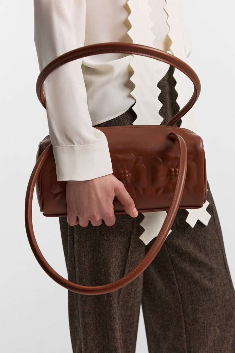 Brown PODYH top handle bag with bas relief design, featuring a stylish and elegant bag with textured detailing.