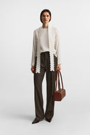 Brown PODYH top handle bag with a detailed bas relief design, showcasing a stylish and elegant accessory.