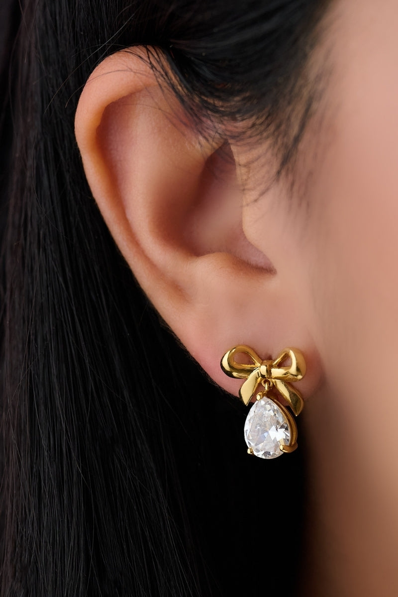 Gold Amelia Scott bow stud earrings with clear CZ stones, featuring a delicate bow design and shiny finish.