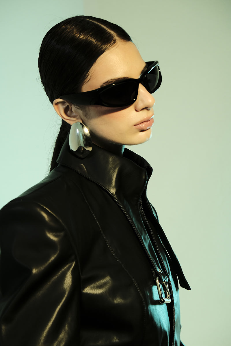 Black faux leather belt-neck blazer by Blikvanger, featuring a tailored fit and sleek design, shown on a mannequin.
