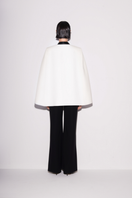 Lili Blanc sleek black and white cape blazer shown from the back, tailored with a stylish draped design and structured fit.