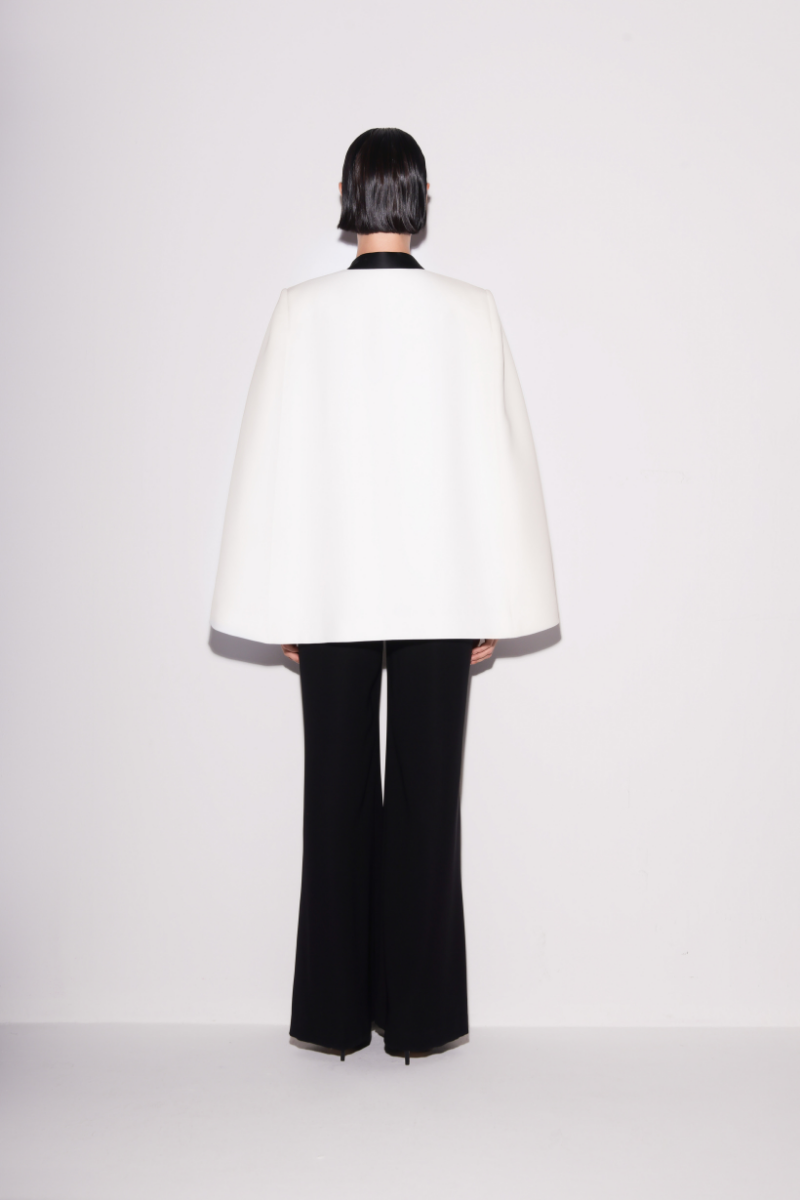 Lili Blanc sleek black and white cape blazer shown from the back, tailored with a stylish draped design and structured fit.