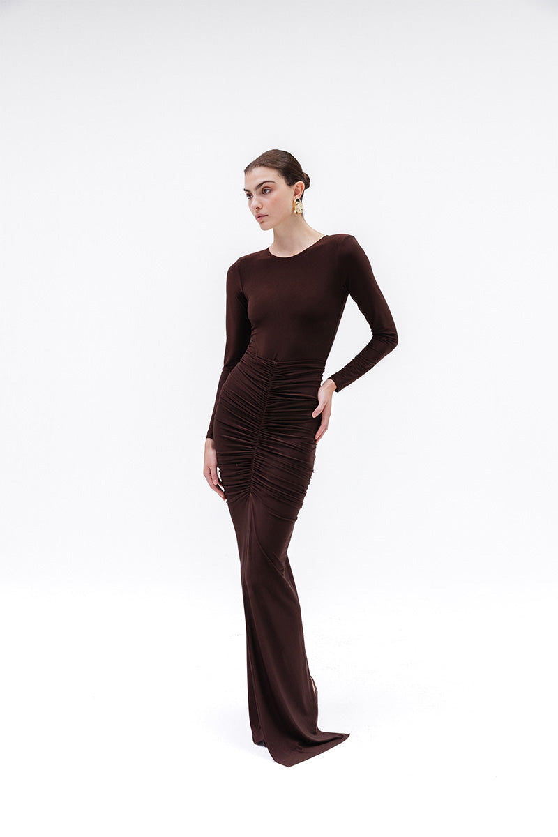 Brown Azalea maxi skirt by Studio NK, flowing fabric with a relaxed fit, shown on a model in a natural outdoor setting.