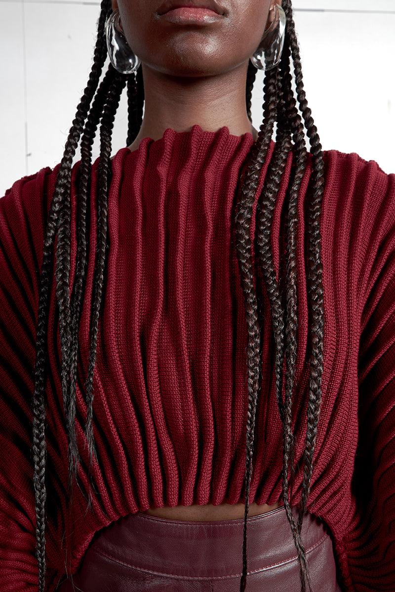 Wine red accordion snail sweater by MAZ Manuela Álvarez featuring a textured, layered design and cozy knit fabric.