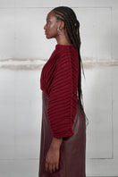 Wine red accordion snail sweater by MAZ Manuela Álvarez featuring textured, layered knit design and long sleeves.