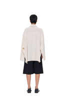 Back view of URA Alfie Cape in ivory, stylish shirt with cape detail, showcasing elegant design and fabric texture.
