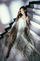 White Valenciani all-over fringed maxi dress with flowing fabric and detailed fringe accents, perfect for summer or special occasions.