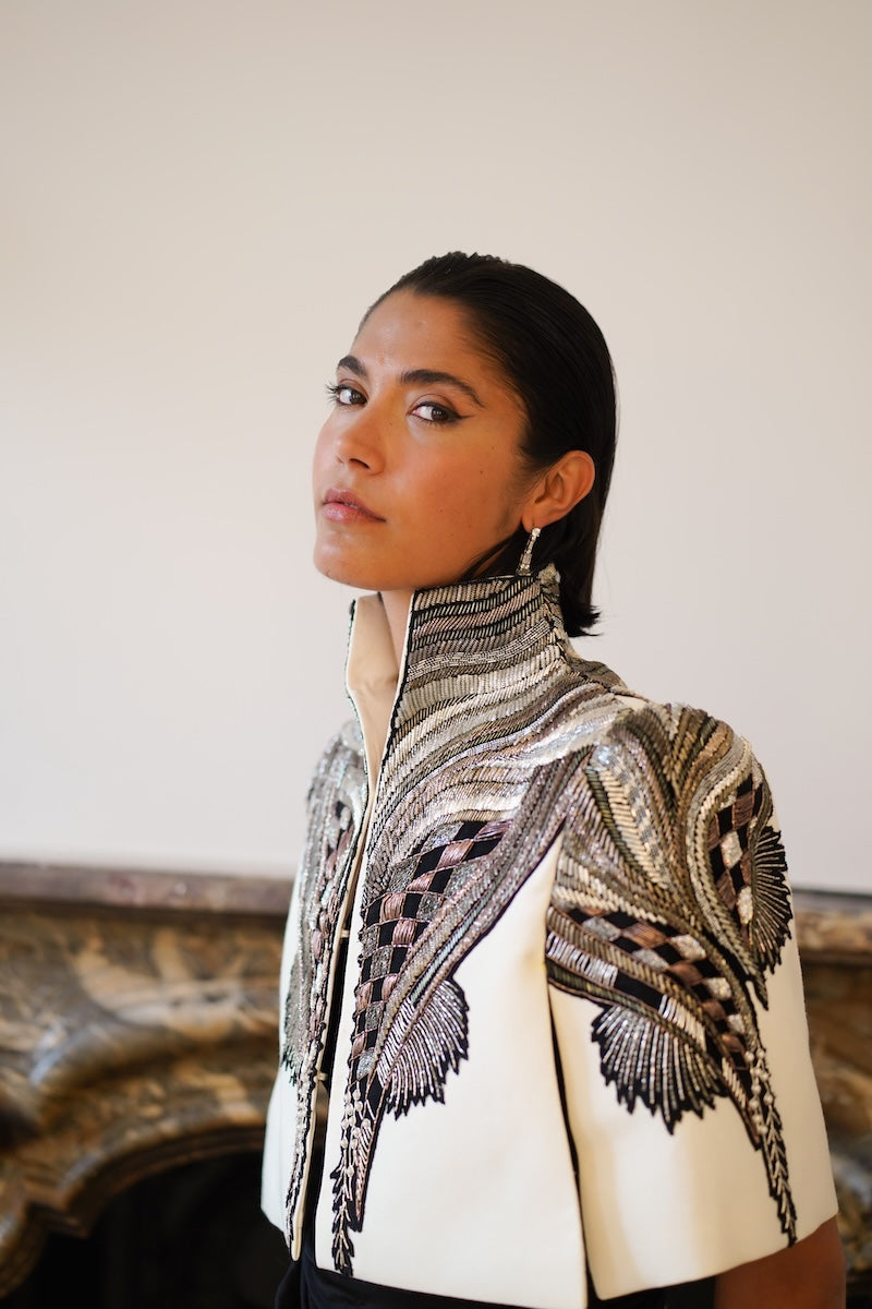 Nadya Shah All About Eve capelet in ivory, stylish jacket with draped design, shown from side view.