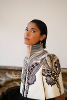 Nadya Shah All About Eve capelet in ivory, stylish jacket with elegant drape and detailed design, shown from side view.