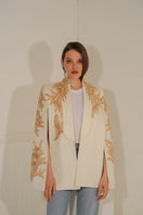 Nadya Shah Alya ivory tuxedo cape draped over shoulders, elegant jacket with tailored design and luxurious fabric.