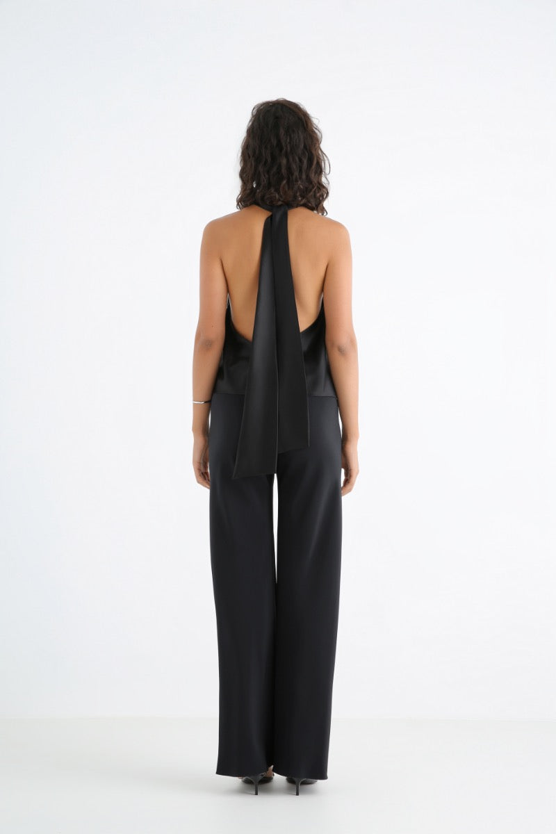 Serenity Amore black silk-satin backless halter-neck top shown on a model, featuring a sleek, elegant design and adjustable halter straps.