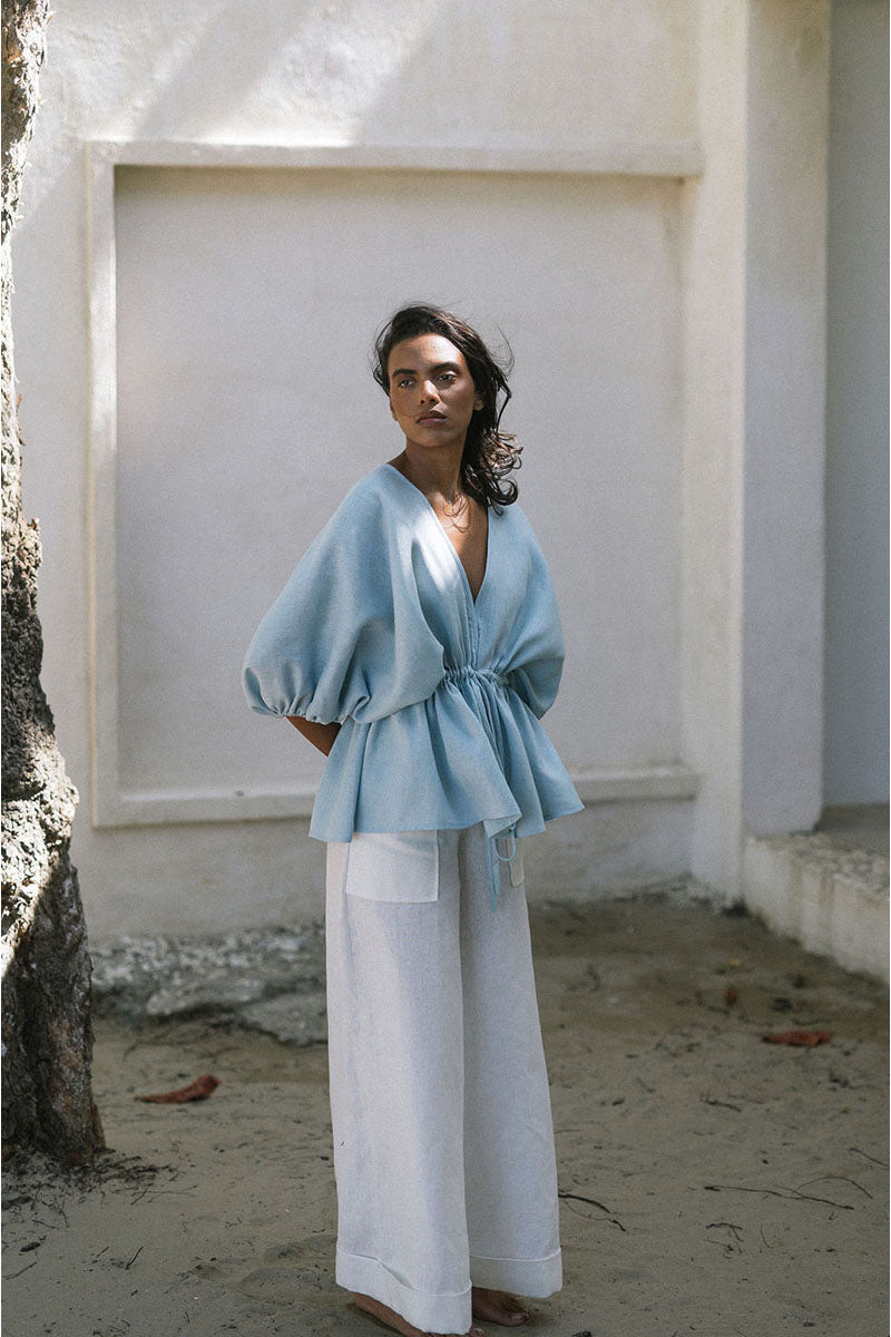 Light blue ANA + MARIA Ani blouse, a stylish women's top with a relaxed fit and soft fabric, displayed on a neutral background.
