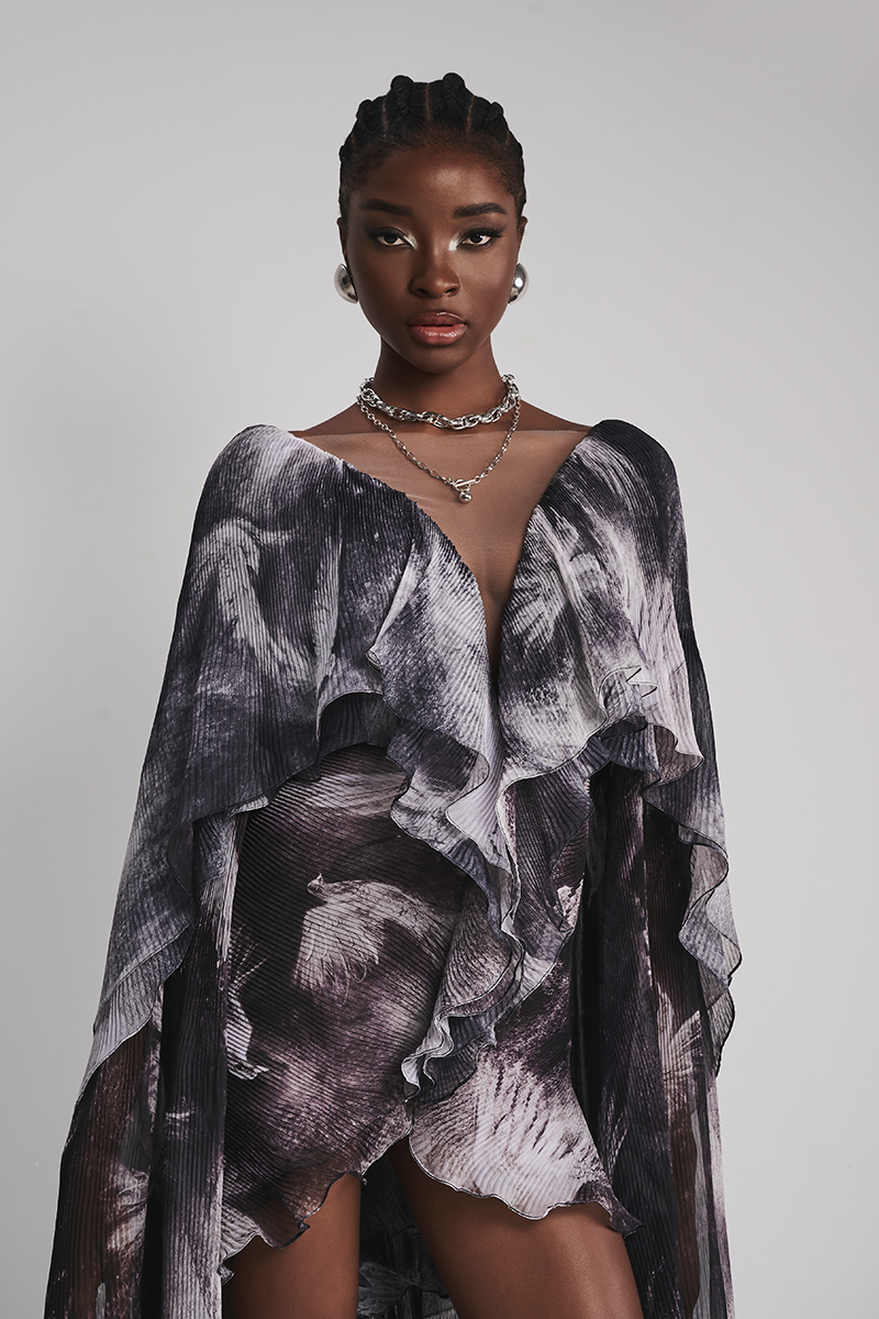 Black Le Thanh Hoa Soaring Doves Maxi Dress displayed on a hanger with flowing fabric and intricate dove pattern.