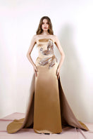 Rayane Bacha Aurea Gown in gold, elegant evening dress with intricate design, flowing fabric, and detailed embellishments.