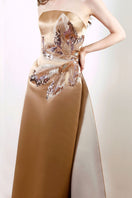 Rayane Bacha Aurea Gown in gold, elegant evening dress with intricate detailing and flowing fabric.