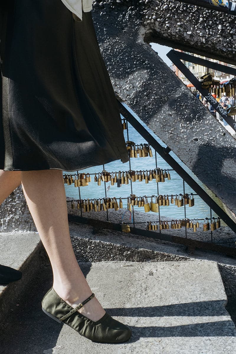 A pair of AERA Aurora gold crystal military satin ballerina flats with decorative embellishments and a sleek satin finish.