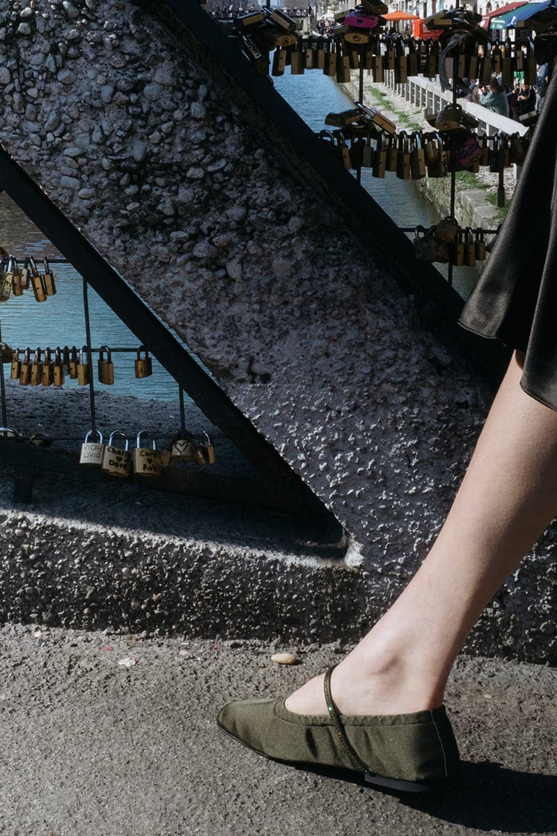 A pair of AERA Aurora gold crystal military satin ballerina flats with decorative details and a sleek, elegant design.