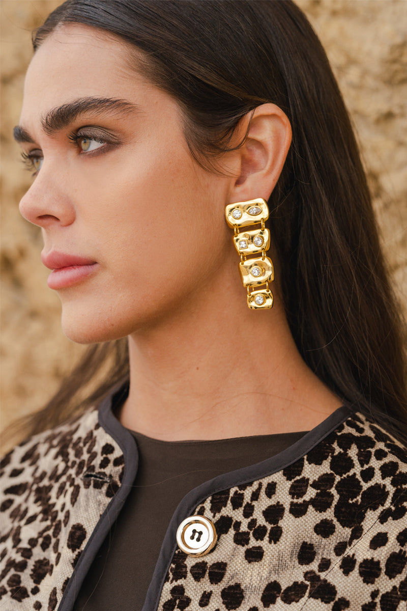Jessica K B.O MINI AURIS earrings with delicate gold hoops and small charm details, displayed on a neutral background.