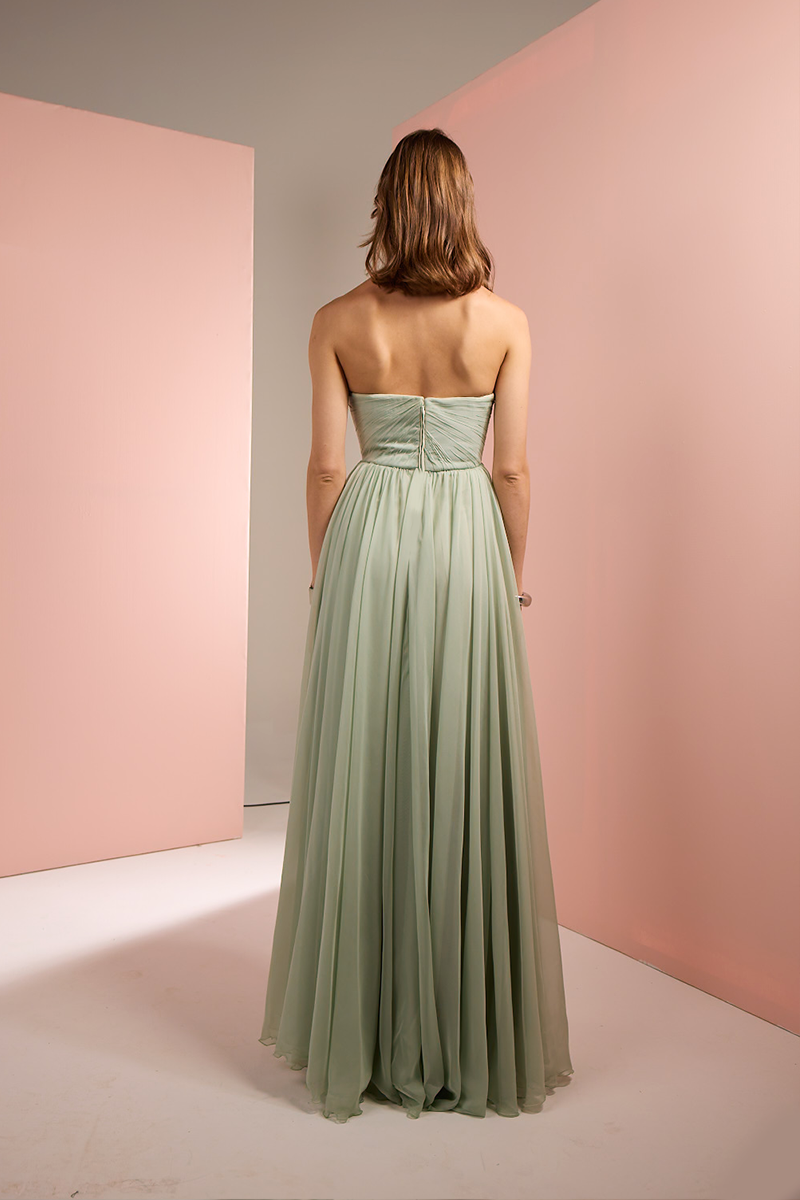 Light green strapless gown by Joanna Andraos shown from the back, featuring elegant draping and a flowing silhouette.