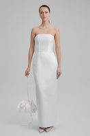 White BAÉ GIGI maxi dress with shoulder bow, flowing fabric, and elegant design, perfect for formal or summer occasions.